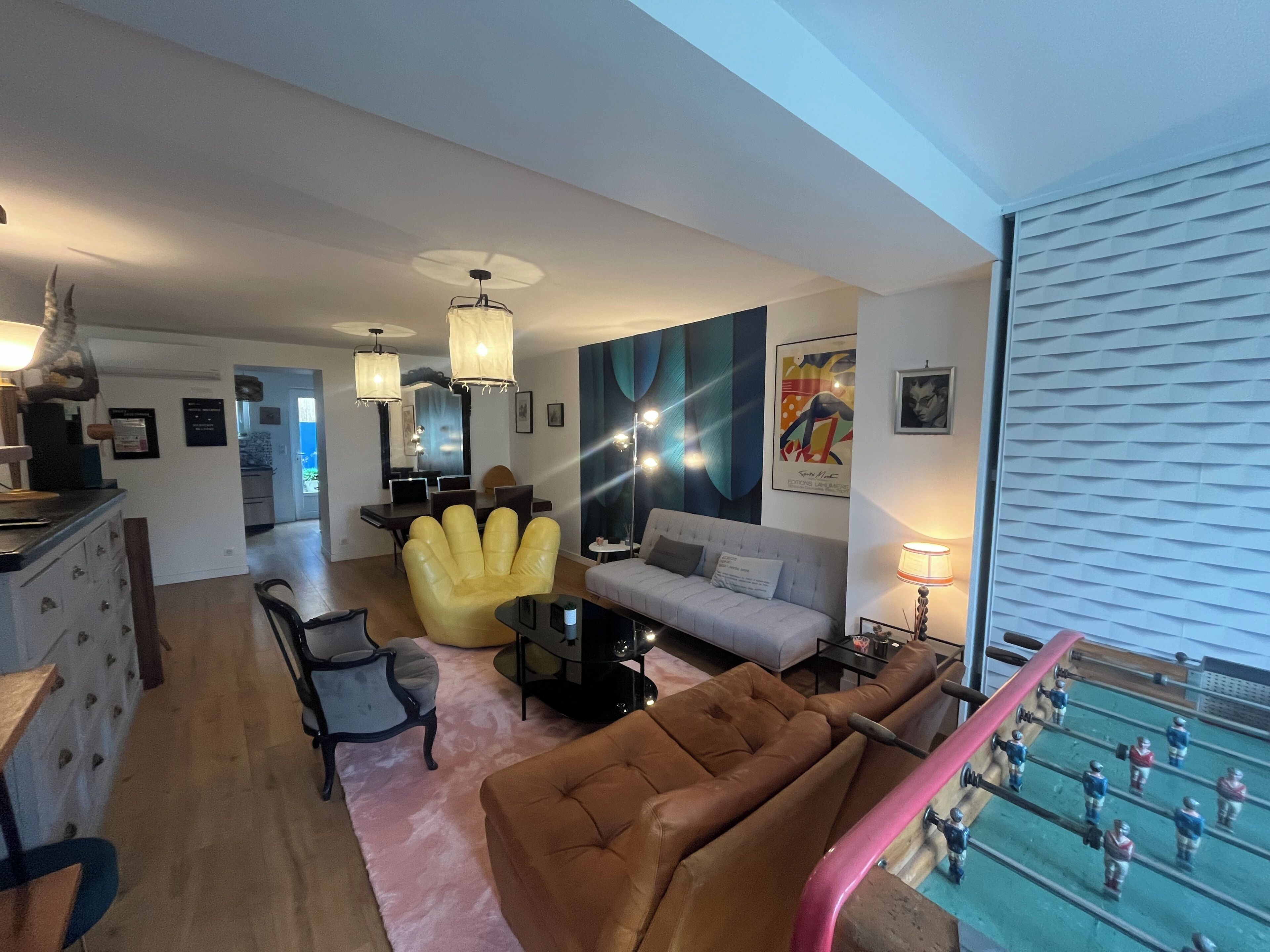 Un salon moderne avec un canapé, un fauteuil et une table de baby-foot.