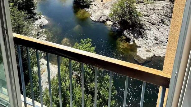 A river surrounded by greenery and hills, viewed from a balcony with a metal railing. - Superb studio with river access and private square (Vals-les-Bains)
