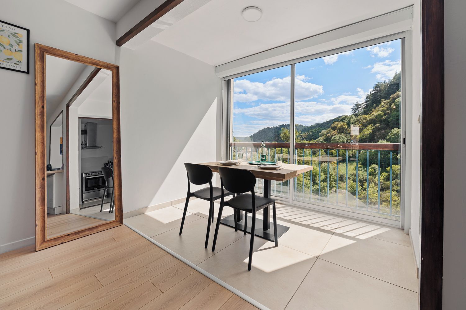 Une pièce moderne dotée d’une table à manger, de chaises et offrant une vue sur un paysage luxuriant grâce à de grandes fenêtres.