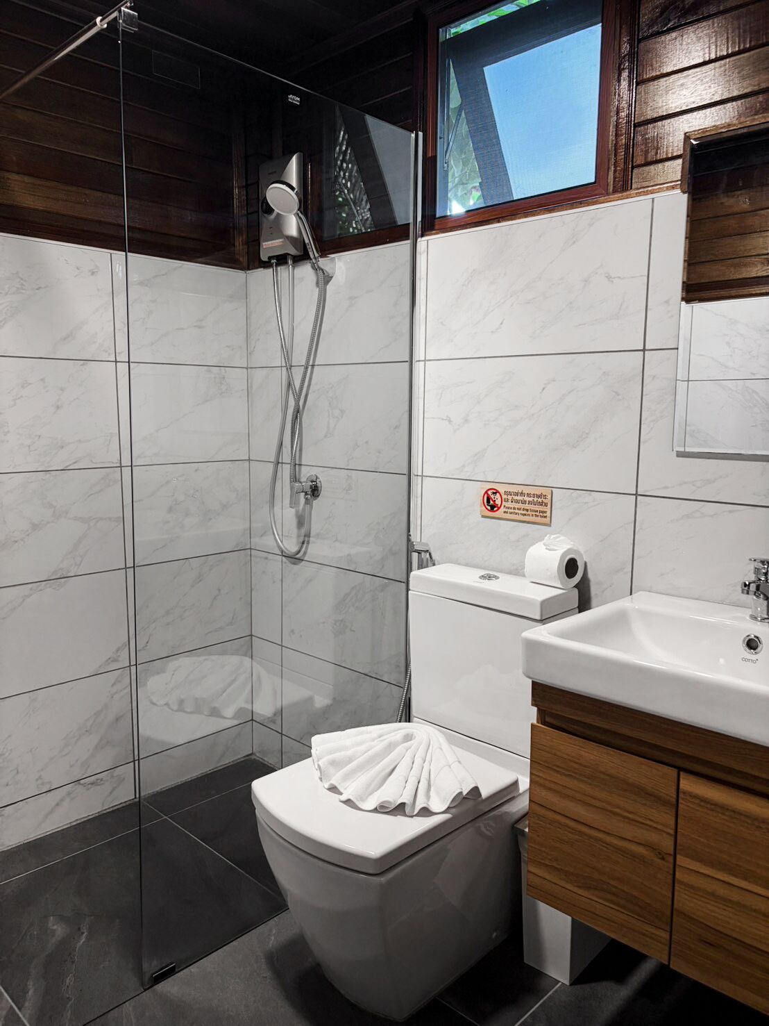 Un baño moderno con ducha de vidrio, inodoro y lavamanos.