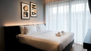 A hotel room with a bed, pillows, a bedside table, and two framed artworks on the wall.
