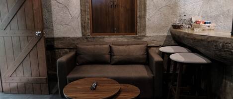 A cozy seating area with a sofa, two round tables, and a bar counter with stools.