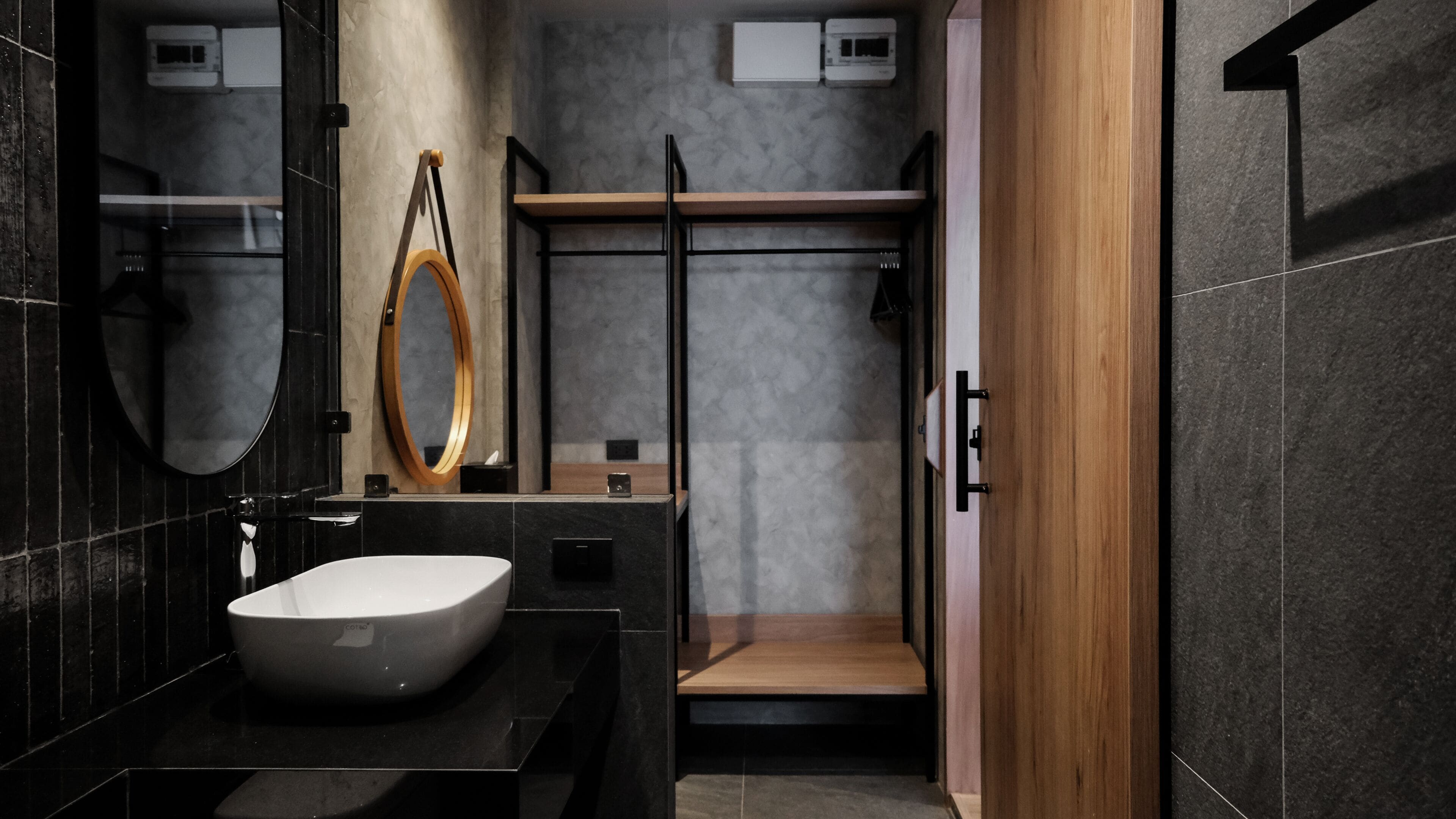 A modern bathroom with a large oval sink, a wooden shelf, and a glass shower enclosure.
