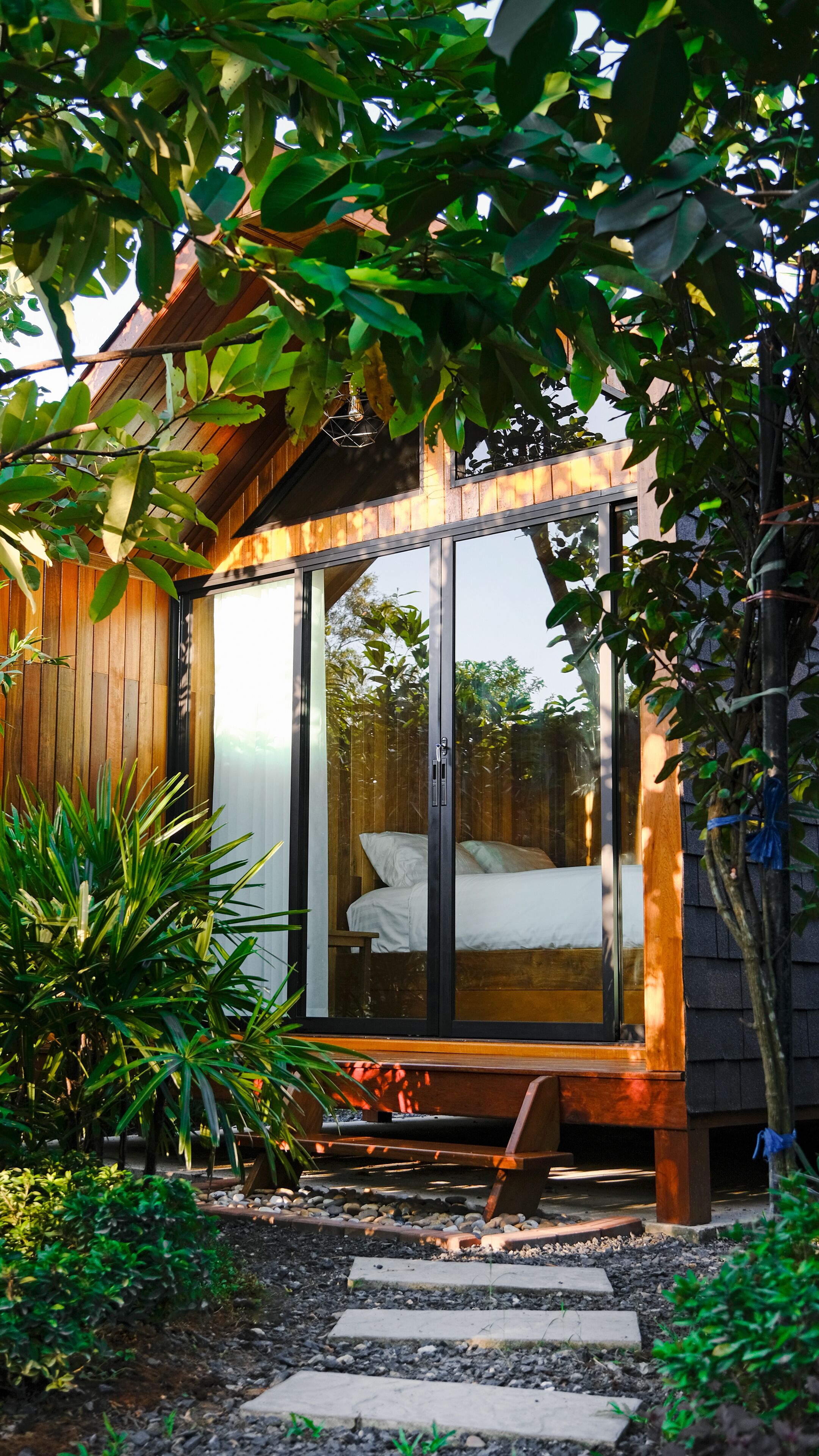 Una casa moderna con un'ampia porta vetrata che dà su una camera da letto con un letto e una panca.