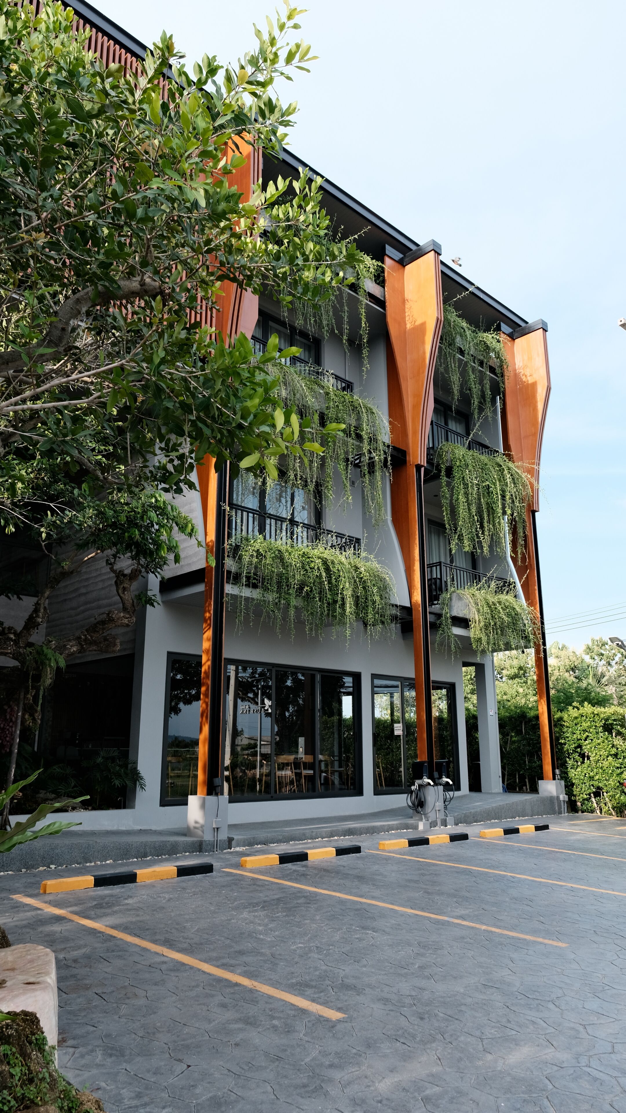 A modern building with a flat roof, large windows, and a parking area with marked spaces.