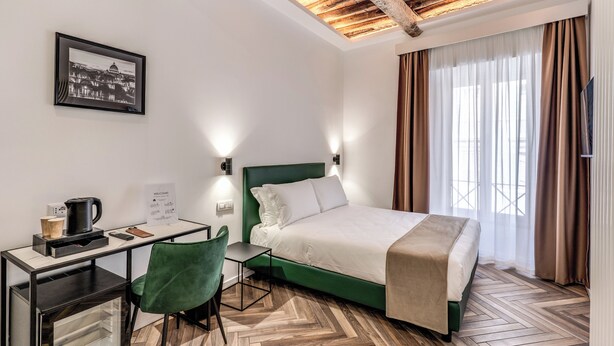A hotel room with a bed, desk, chair, and a framed picture on the wall. - EFFE LUXURY ROOMS (Rome)