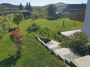 A residential area with a grassy lawn, a small garden, and a paved pathway leading to a building.