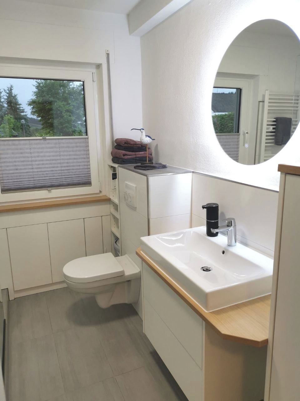 A modern bathroom with a toilet, sink, and window.