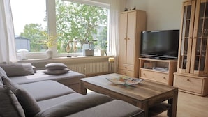A living room with a sofa set, a wooden coffee table, a television, and a cabinet.