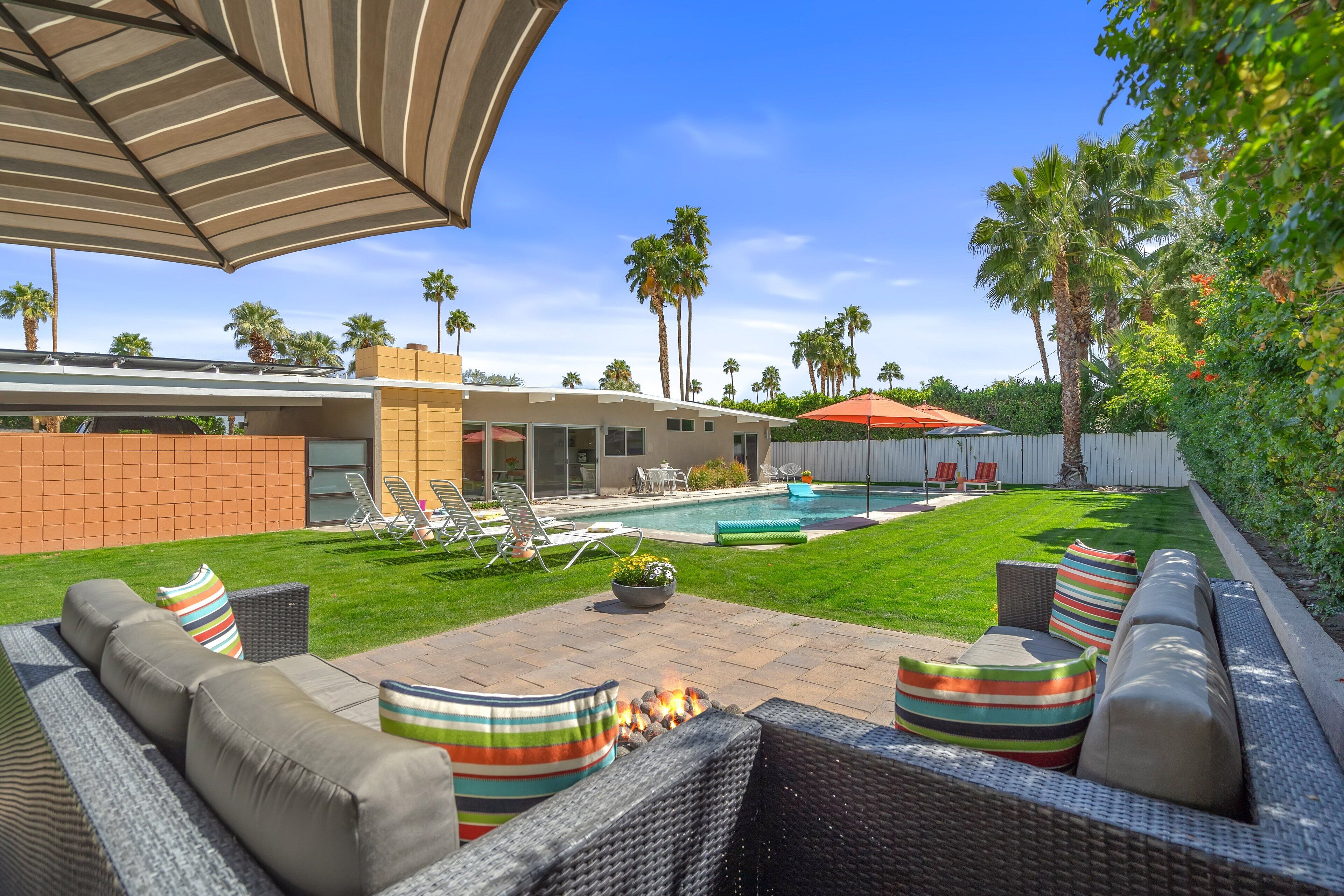 A backyard with a pool, outdoor furniture, and a fire pit.