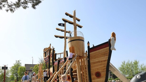 A wooden pirate ship play structure with climbing nets and slides, surrounded by sand and trees. - 5 Star Holiday Home in Wangerland (Wangerland)
