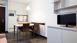 Eine moderne Küche mit Essbereich, einem Flachbildfernseher und einem eingebauten Backofen.
