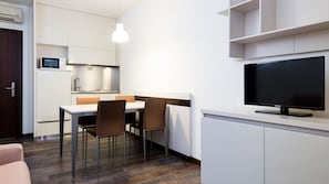 Eine moderne Küche mit Essbereich, einem Flachbildfernseher und einem eingebauten Backofen.