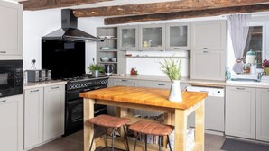 Eine moderne Küche mit Holztisch und Hockern, einem Herd und Schränken.