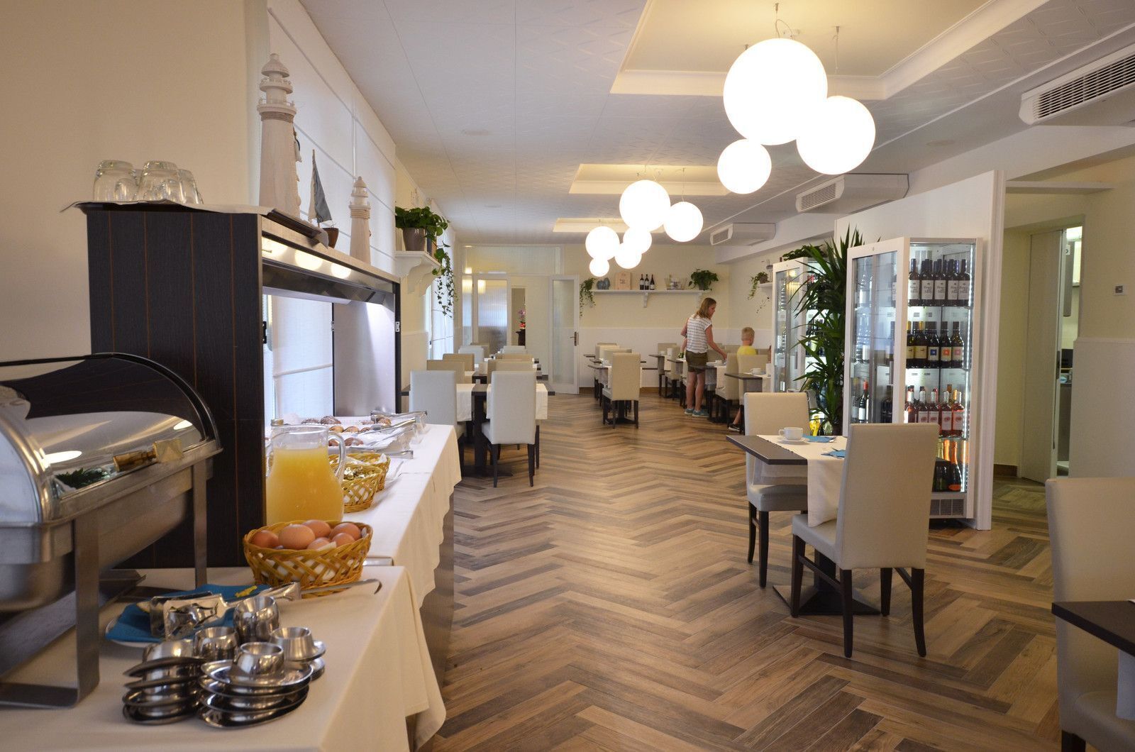 A hotel dining area with buffet, seating, and a wine cooler.