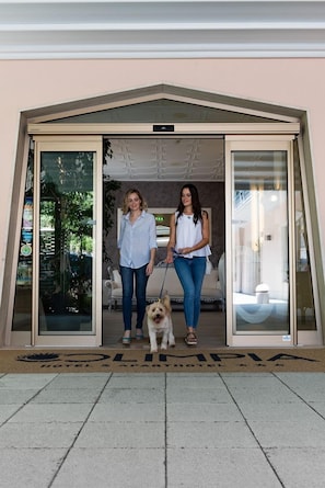 Two people standing in front of a hotel entrance with a dog on a leash. - Cozy bedroom with balcony for one in Bibione (Bibione)