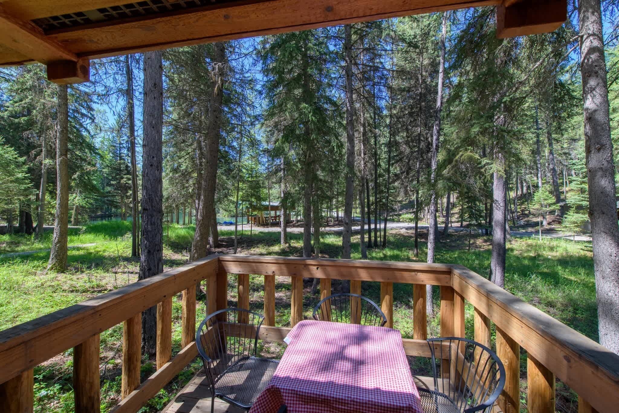 Une terrasse en bois avec une table et des chaises, donnant sur une zone boisée.