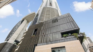 Un immeuble moderne de grande hauteur, doté d’une conception architecturale unique, de nombreux balcons et de grandes fenêtres.