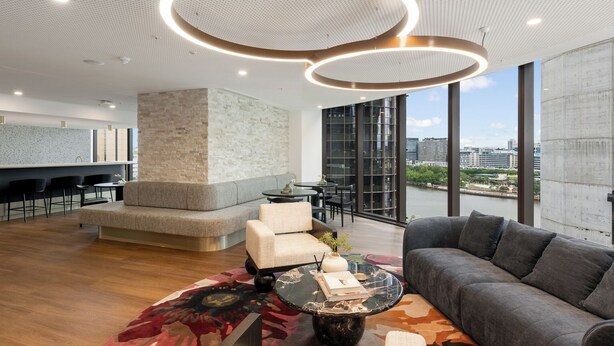 Un salon moderne comprenant un canapé, des fauteuils, une table basse et offrant une vue sur la ville grâce à de grandes fenêtres.