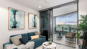 Un salon moderne avec un canapé de couleur turquoise, une table basse ronde et deux tableaux abstraits accrochés au mur.