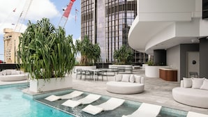 Un espace piscine aménagé sur le toit, avec des chaises longues, un coin repas et un comptoir d’accueil.