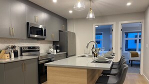 A modern kitchen with grey cabinets, stainless steel appliances, and a central island with bar stools.