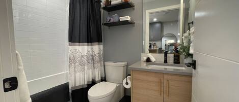 Un baño moderno con inodoro, lavamanos y zona de ducha.