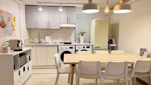 Une cuisine moderne avec des meubles blancs, une table à manger en bois, ainsi qu’un lave-linge et un sèche-linge intégrés.
