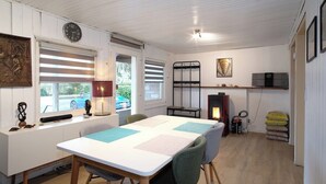 A cozy room with a white table, chairs, a clock, a fireplace, and a window with blinds.