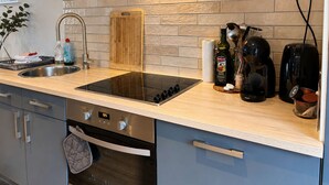 Une cuisine moderne dotée d’une cuisinière intégrée, d’un évier en acier inoxydable et d’un plan de travail en bois.