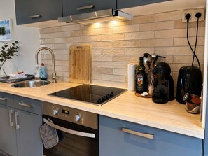 Une cuisine moderne dotée d’une cuisinière intégrée, d’un évier en acier inoxydable et d’un plan de travail en bois.