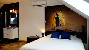 Une chambre moderne avec un grand lit, une table de chevet, une commode, un climatiseur et une œuvre d’art accrochée au mur.