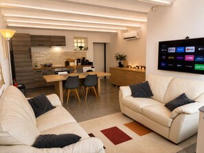 A modern living room with a sofa, a coffee table, and a TV mounted on the wall displaying various streaming services.