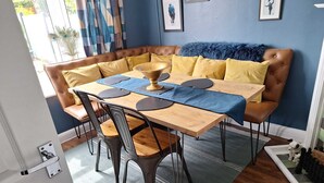 Ein Essbereich mit einem Holztisch, schwarzen Stühlen und einem braunen Ledersofa mit gelben Kissen.