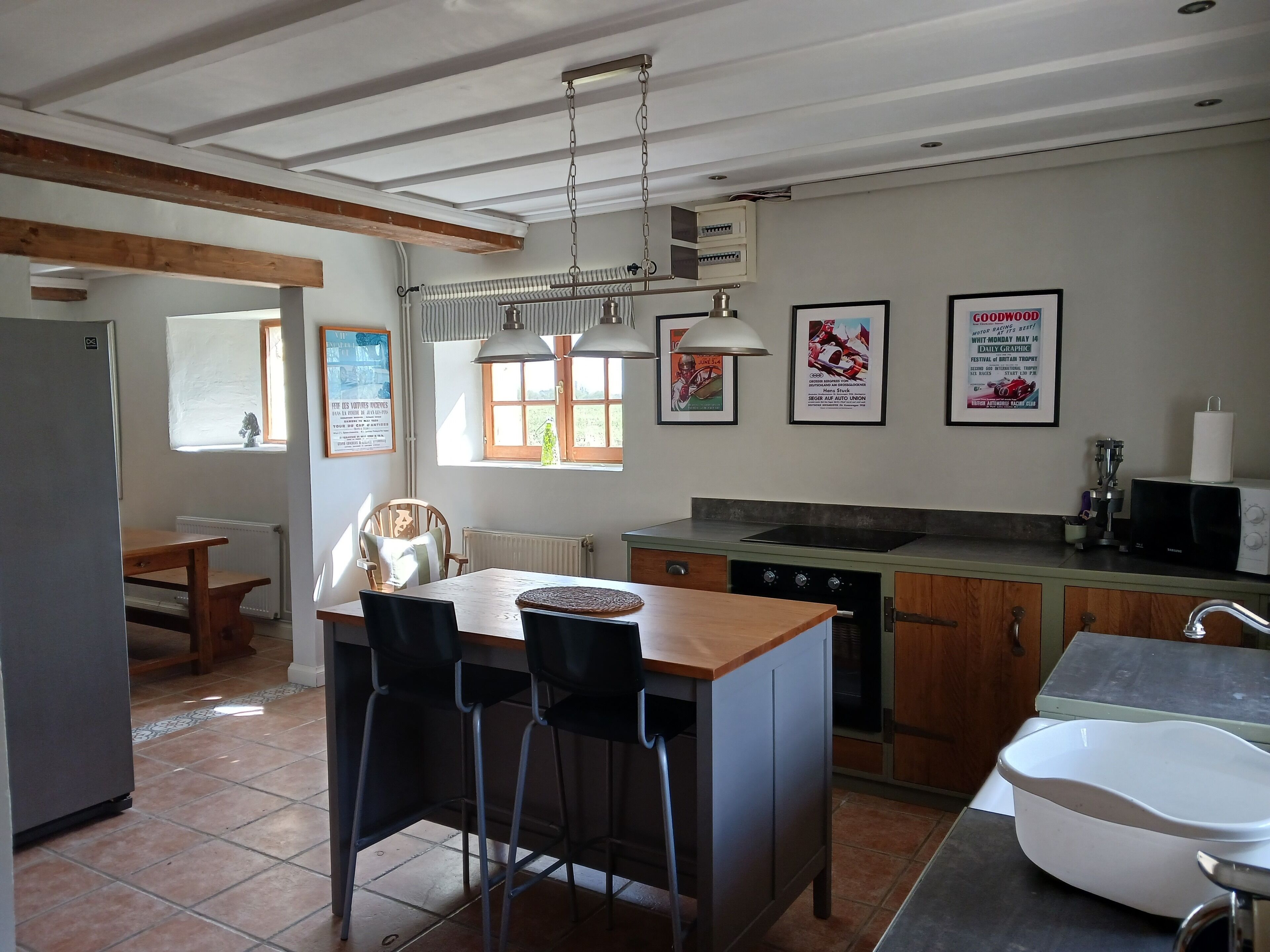 A kitchen with a central island, bar stools, a microwave, and a sink.