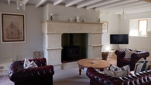 A living room with a fireplace, leather sofas, a wooden coffee table, and a television mounted on the wall.