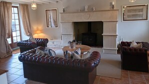 A cozy living room with a fireplace, leather sofas, a round coffee table, and a stone fireplace surround.