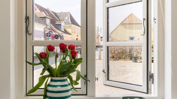 A window with a striped vase of red tulips and a candle holder on the sill. - 6 Person Holiday Home in Marstal (Marstal)