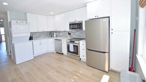 Een moderne keuken met witte kasten, roestvrijstalen apparatuur en een betegelde spatwand.