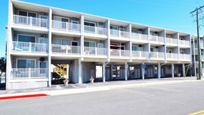 A multi-story motel with balconies, a parking area, and a clear blue sky. - Mirabella 1D-Oceanside 122nd St, AC, Free WiFi. (Ocean City)
