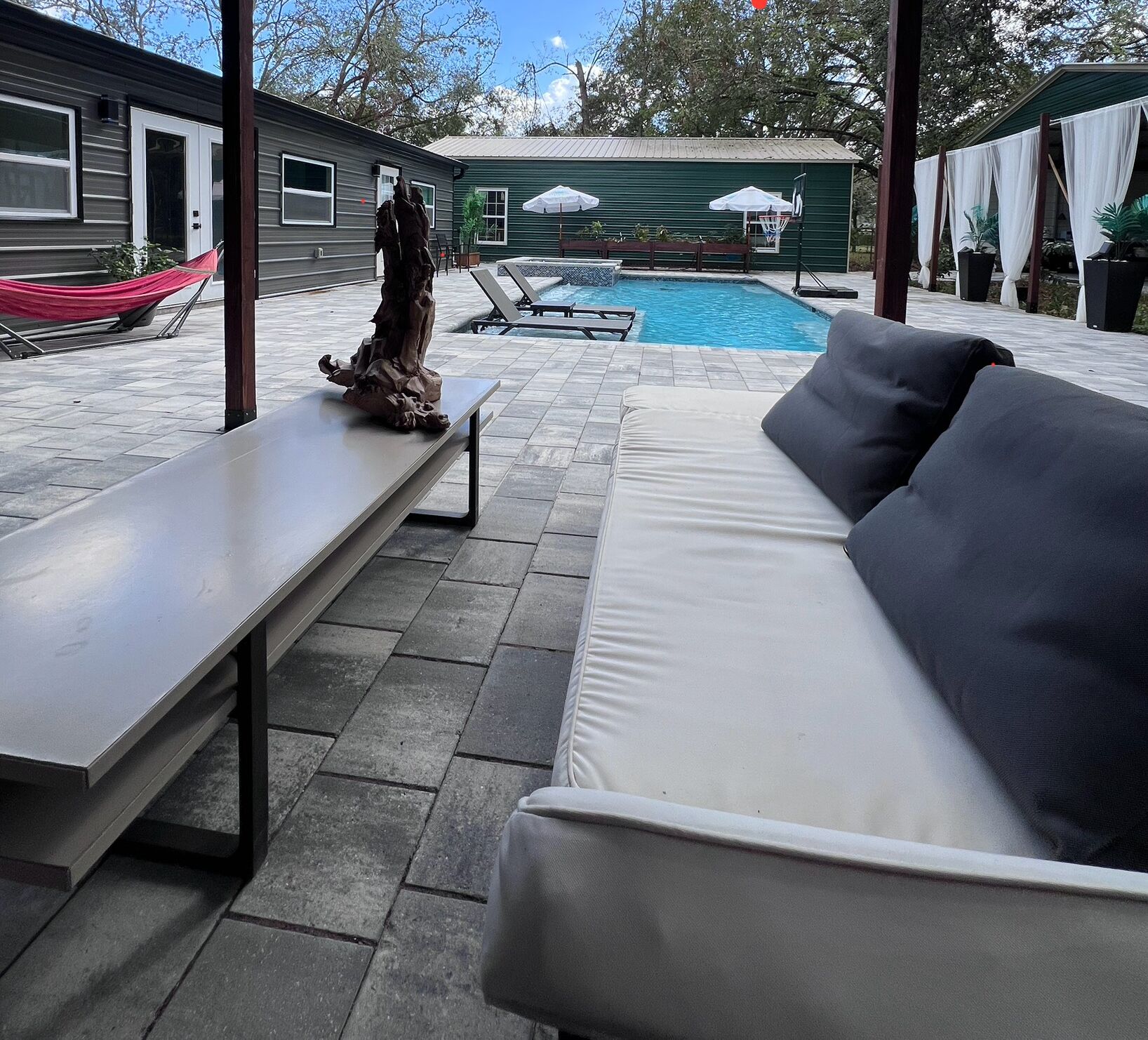 Ein Poolbereich mit einer weißen Couch, einer Bank und einer Hängematte.