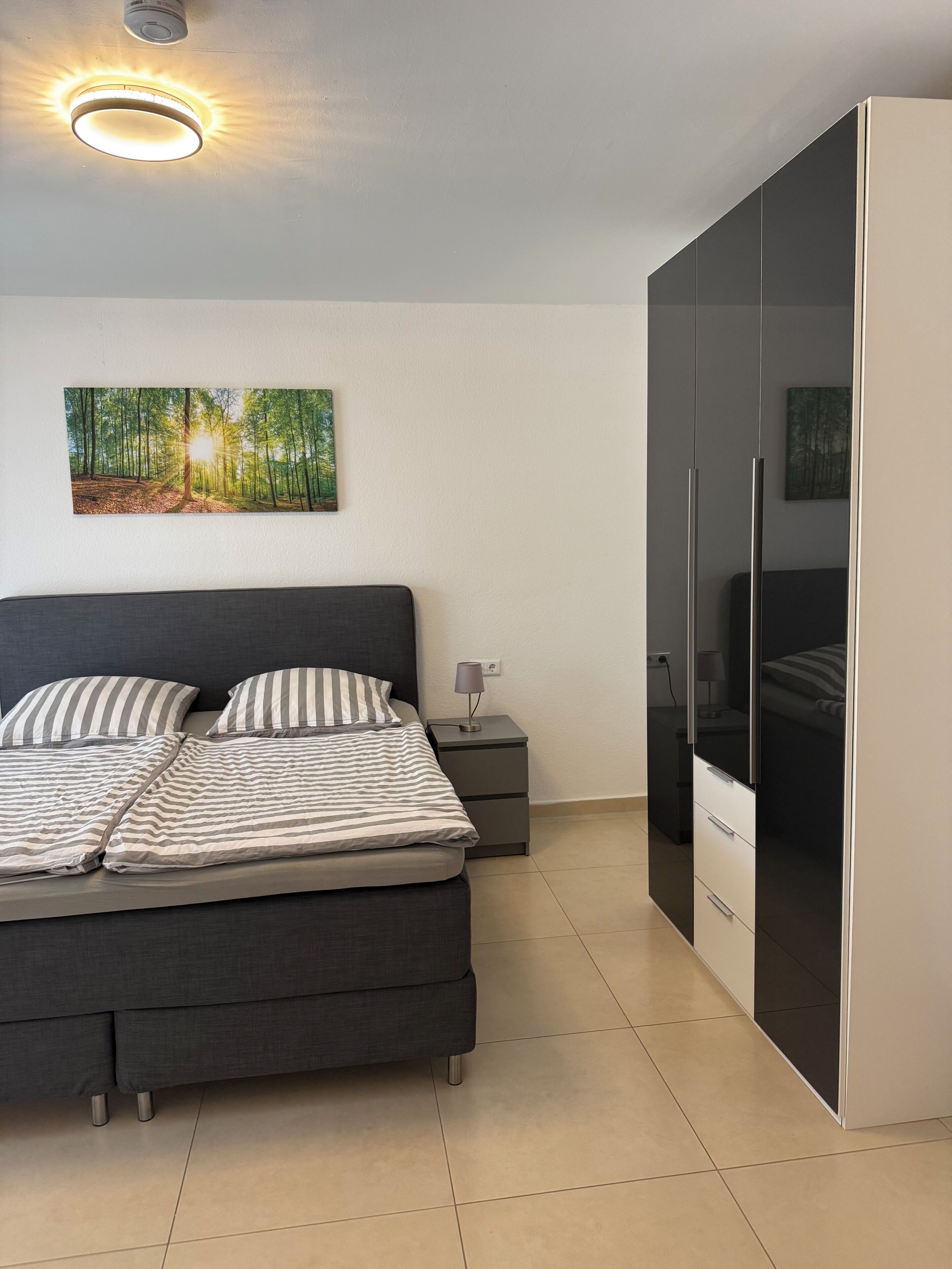 Une chambre à coucher avec un lit, une table de chevet, une armoire et un tableau au mur.