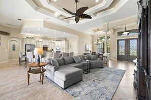 A spacious living room with a sectional sofa, a dining area, and a kitchen in the background.