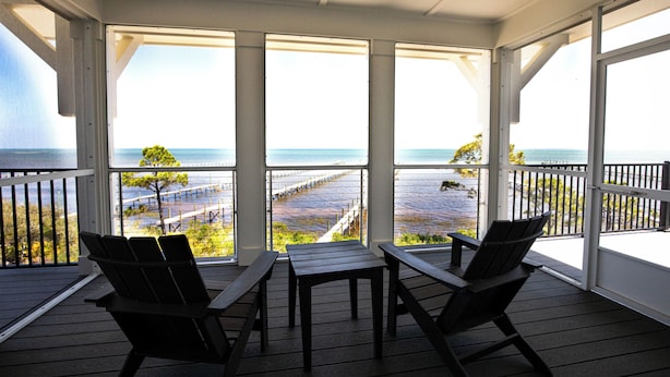 A covered outdoor seating area with a view of the ocean and a pier. - Bayfront oasis with private dock, pool, elevator and easy ADA beach access. (Port St Joe)