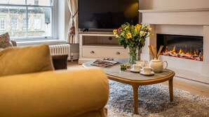 Un salon comprenant un canapé, une table basse, une cheminée, un téléviseur et une fenêtre donnant sur des immeubles.