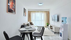 A modern living room with a dining area, a water dispenser, and a flat-screen TV. - One Bedroom Apartment in Kilimani, near Yaya Centre (Nairobi)