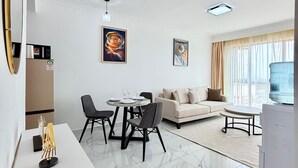 A modern living room with a dining area, a sofa, and a TV. - One Bedroom Apartment in Kilimani, near Yaya Centre (Nairobi)