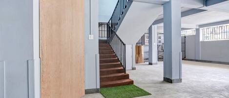 Un interior espacioso con una escalera que lleva a niveles superiores, suelo de concreto y una pared de acento de madera.