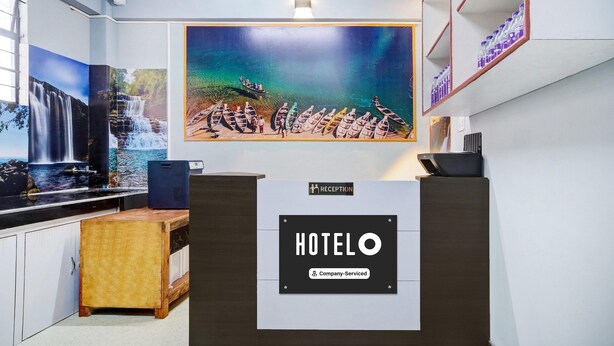 A reception desk with a "HOTELO" sign, a large painting of a waterfall and boats, and a shelf with bottled water. - Hotel O Lapalang Shillong (Shillong)