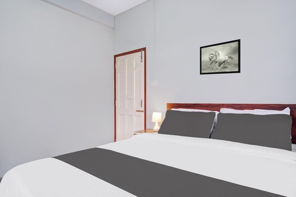 A hotel room with a bed, a nightstand, a lamp, a framed picture on the wall, and a door. - Hotel O Lapalang Shillong (Shillong)